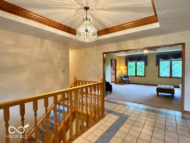 hallway with a raised ceiling, light colored carpet, a chandelier, light tile patterned flooring, and baseboards