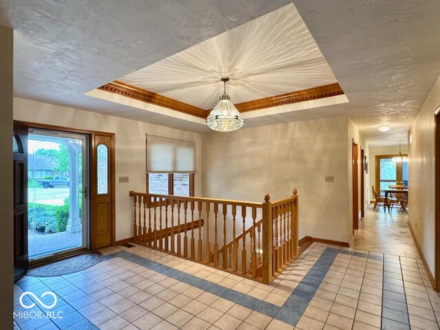 foyer featuring a tray ceiling, a chandelier, and light tile patterned floors