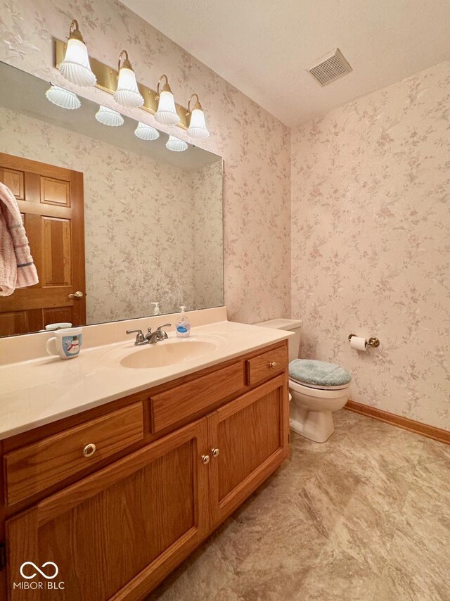 bathroom featuring vanity, toilet, and baseboards