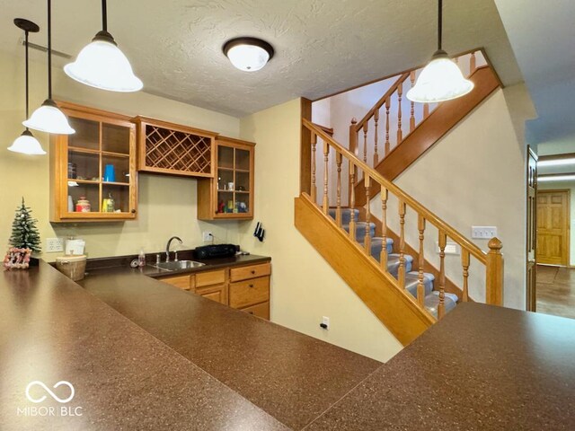 bar area featuring a sink, a textured ceiling, hanging light fixtures, and stairway