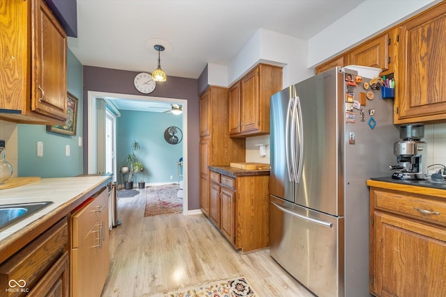 kitchen with freestanding refrigerator, brown cabinets, a ceiling fan, and light wood finished floors