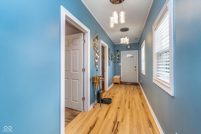 doorway featuring an inviting chandelier, baseboards, and light wood-type flooring