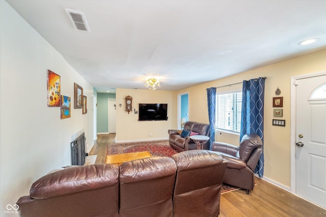 living area with light wood-style floors, baseboards, a fireplace, and visible vents
