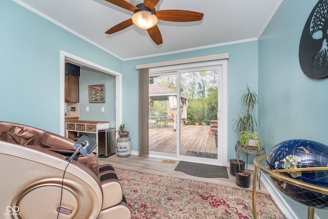 interior space featuring baseboards, ornamental molding, a ceiling fan, and wood finished floors