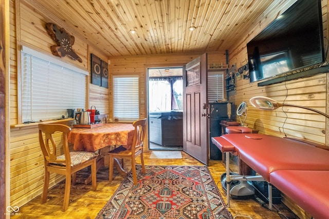 dining room featuring wood walls, light wood finished floors, and wooden ceiling