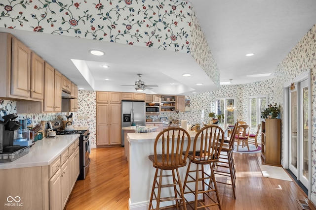 6821 Ripple Creek Dr, Lafayette, IN 47905 - kitchen featuring a kitchen breakfast bar, light countertops, light wood-style floors, stainless steel appliances, and wallpapered walls