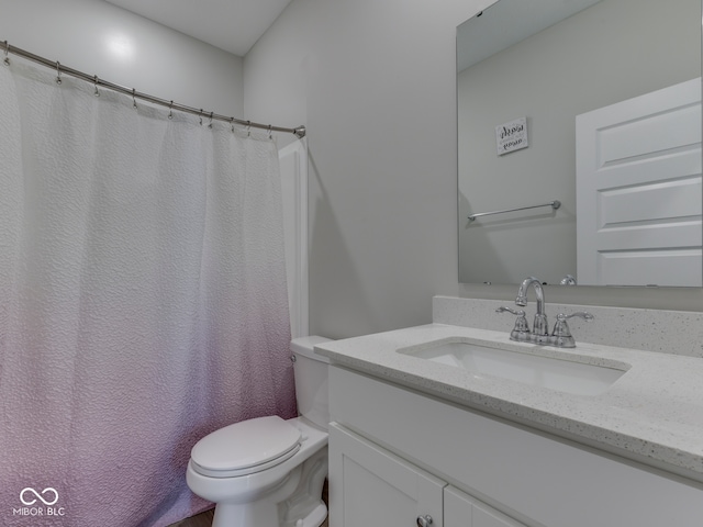 bathroom featuring toilet, vanity, and a shower with curtain