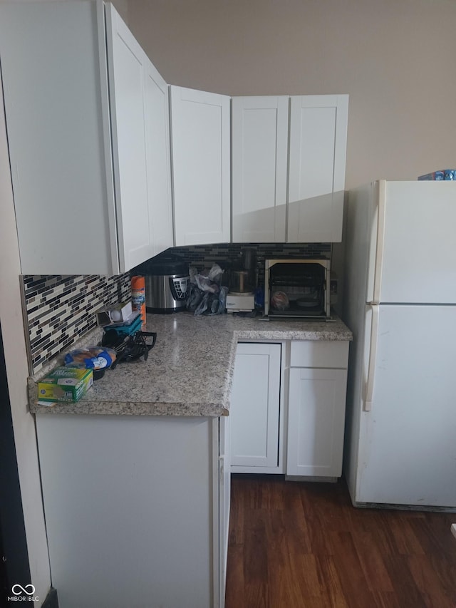 kitchen with freestanding refrigerator, white cabinets, dark wood finished floors, light countertops, and decorative backsplash