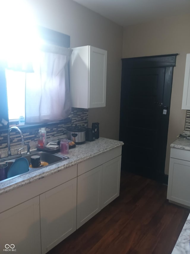 kitchen with white cabinetry, dark wood finished floors, decorative backsplash, and a sink