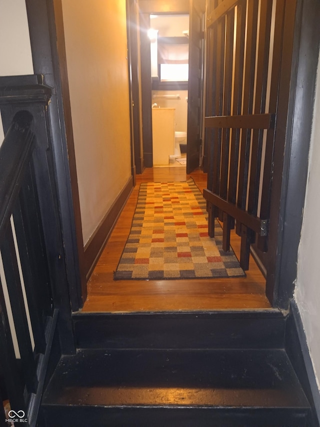 corridor featuring baseboards and wood finished floors
