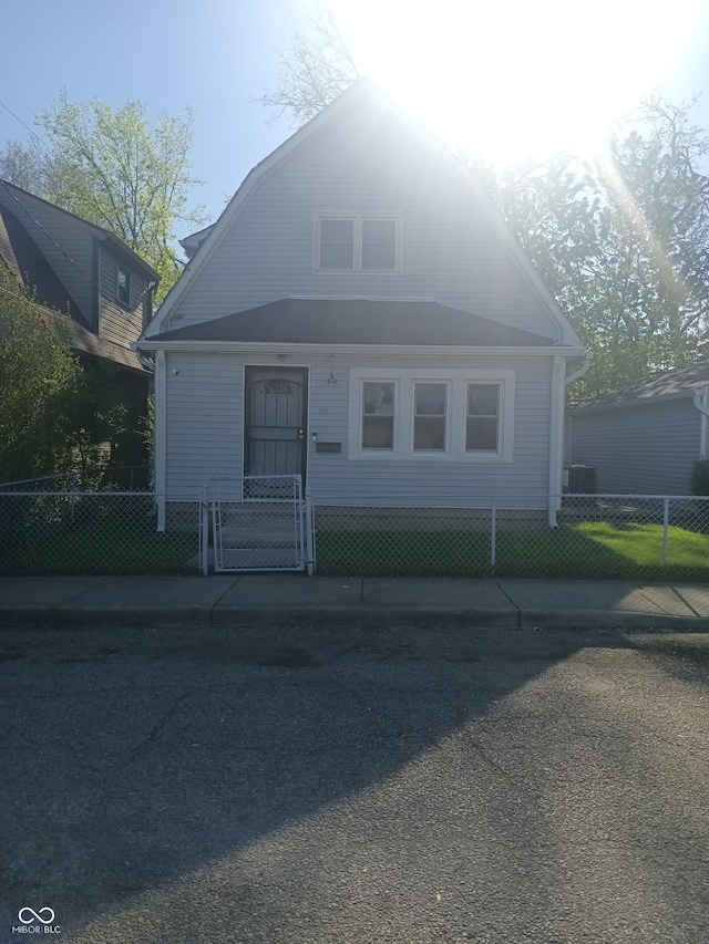 bungalow-style house with cooling unit, a gambrel roof, and a fenced front yard