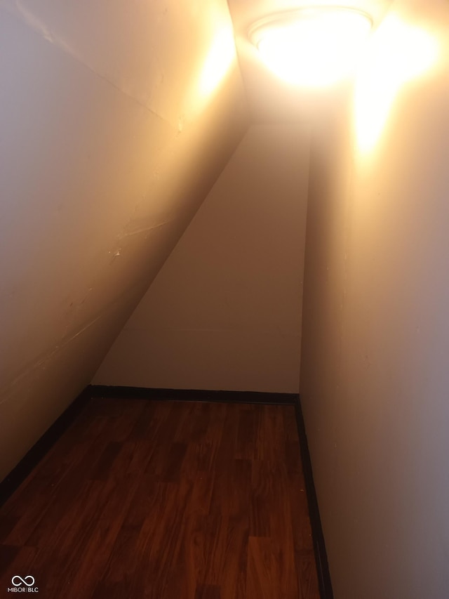 bonus room featuring vaulted ceiling and dark wood-type flooring
