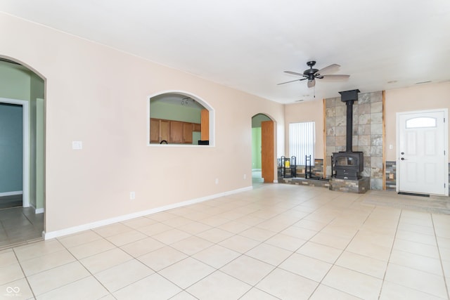 2761 Winding Creek Ln, Greenfield, IN 46140 - unfurnished living room with a wood stove, a ceiling fan, arched walkways, and light tile patterned floors