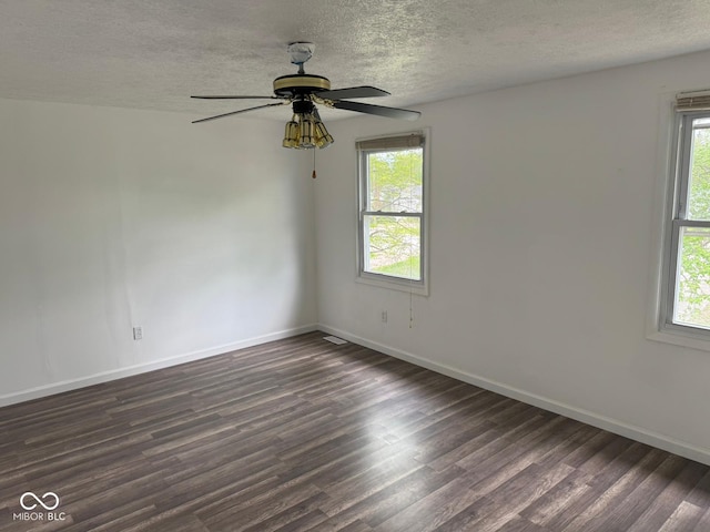 unfurnished room with a textured ceiling, baseboards, plenty of natural light, and dark wood-type flooring