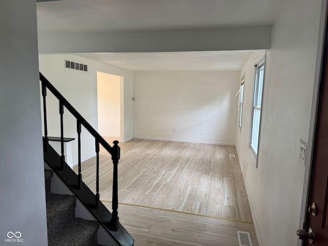stairway with baseboards, visible vents, and wood finished floors