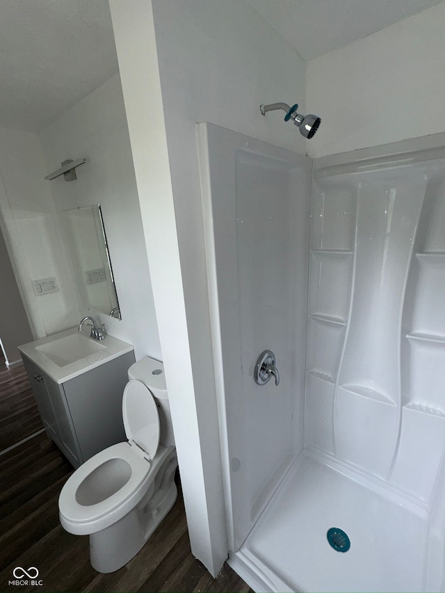 full bath featuring toilet, walk in shower, vanity, and wood finished floors