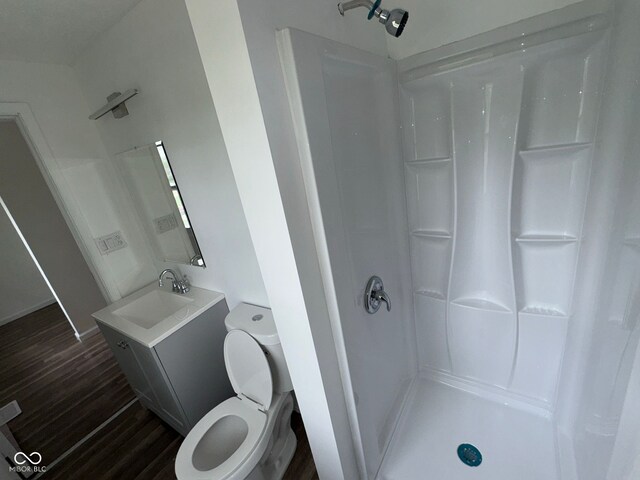 full bathroom featuring toilet, walk in shower, vanity, and wood finished floors
