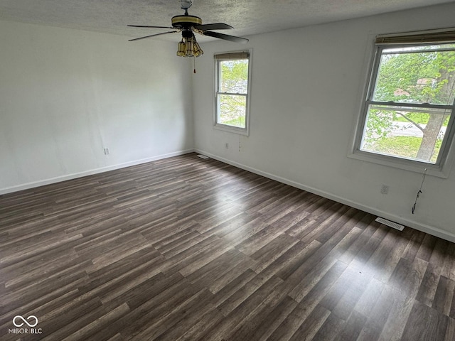 unfurnished room with baseboards, dark wood-style flooring, visible vents, and a textured ceiling