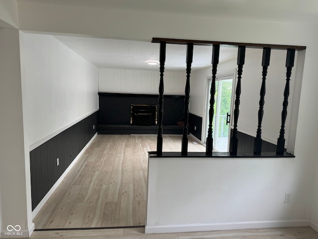 interior space featuring a fireplace, wood walls, a wainscoted wall, and wood finished floors
