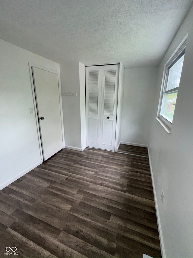 unfurnished bedroom with baseboards, a closet, and dark wood finished floors