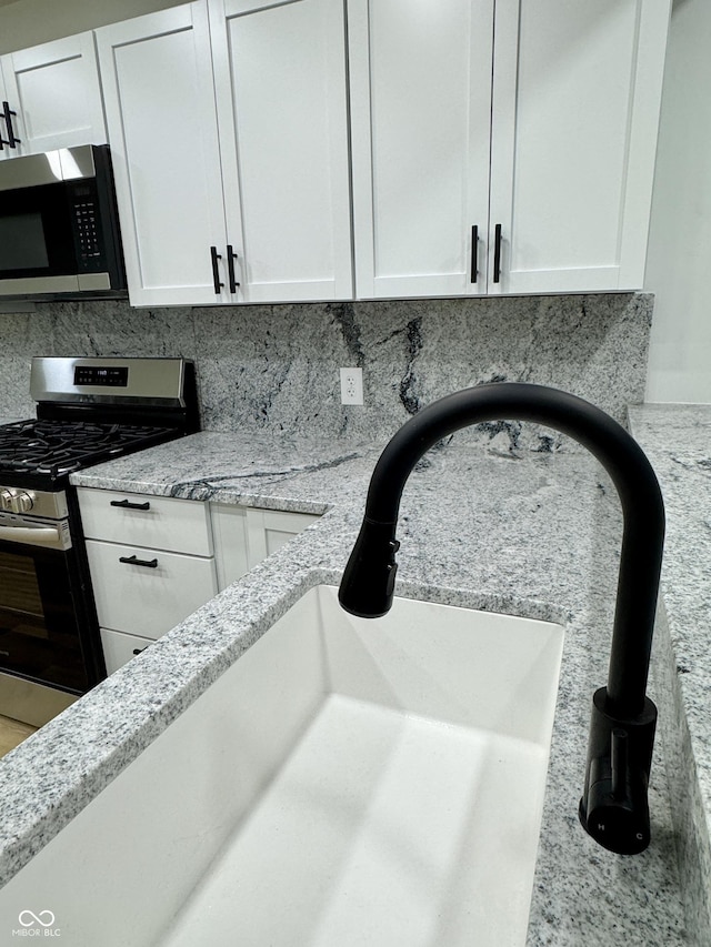 interior details with light stone counters, stainless steel appliances, and white cabinets