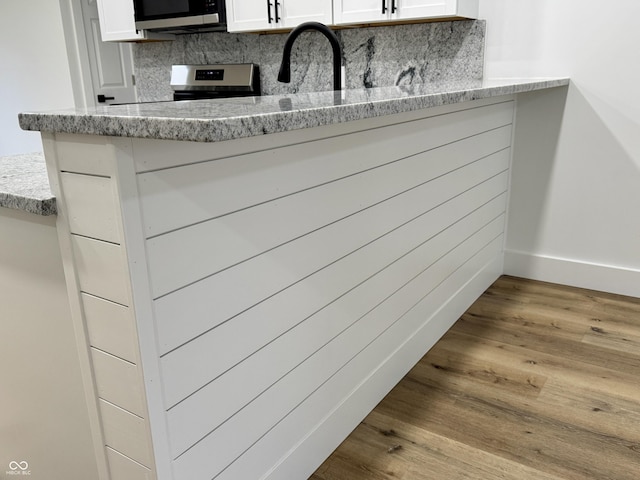 interior details with appliances with stainless steel finishes, tasteful backsplash, baseboards, and wood finished floors