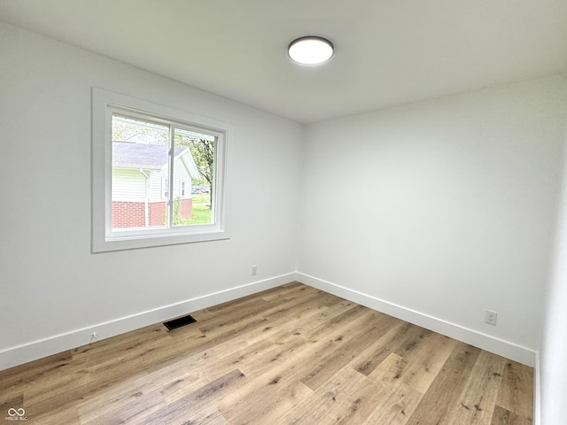 spare room featuring light wood-style floors, visible vents, and baseboards