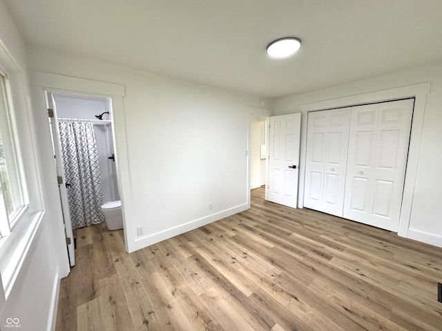 unfurnished bedroom with ensuite bath, baseboards, a closet, and light wood-style floors