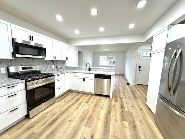 kitchen with white cabinetry, stainless steel appliances, a peninsula, and a sink