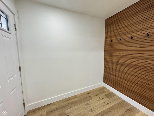 mudroom featuring baseboards, wood walls, and light wood-style floors