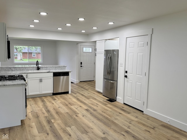 kitchen with recessed lighting, appliances with stainless steel finishes, a sink, and light wood-type flooring