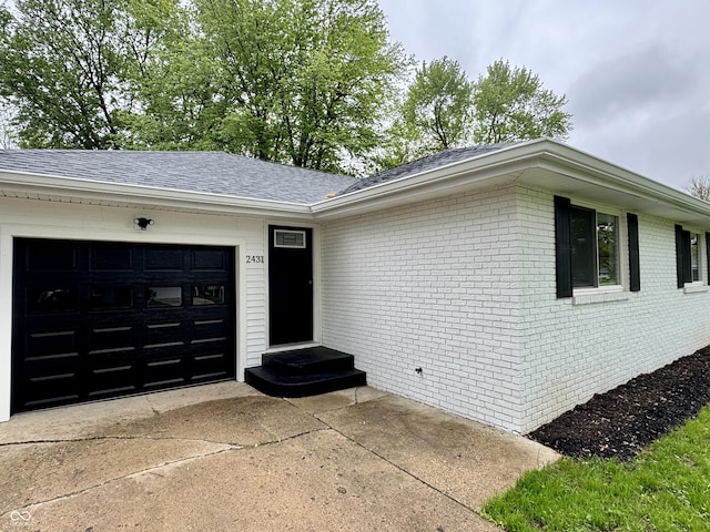 view of front of property with concrete driveway, roof with shingles, brick siding, and an attached garage