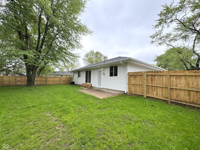 rear view of property featuring a lawn and a fenced backyard