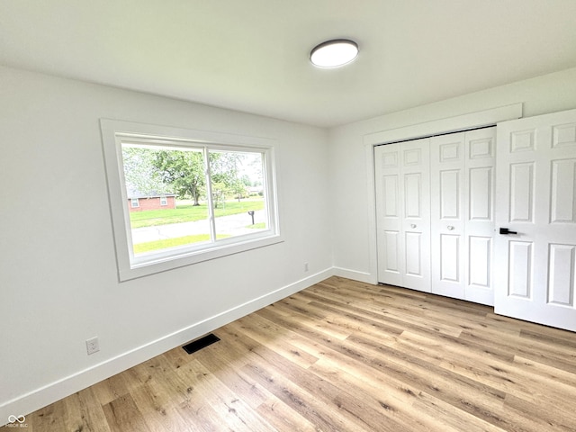 unfurnished bedroom featuring baseboards, a closet, light wood-style flooring, and visible vents