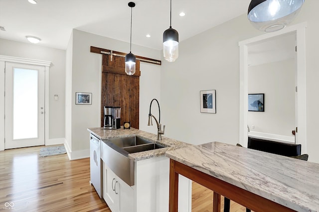 829 Olive St, Indianapolis, IN 46203 - kitchen featuring white dishwasher, a sink, light stone countertops, light wood-style flooring, and pendant lighting