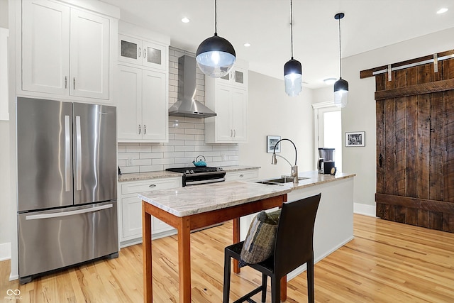 829 Olive St, Indianapolis, IN 46203 - kitchen featuring stainless steel appliances, wall chimney range hood, a sink, light wood finished floors, and recessed lighting
