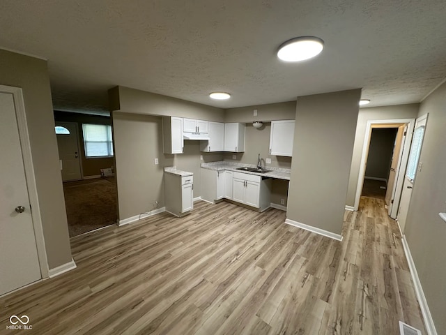 2453 Larnie Ln, Indianapolis, IN 46219 - kitchen with light wood finished floors, white cabinetry, under cabinet range hood, a textured ceiling, and light countertops