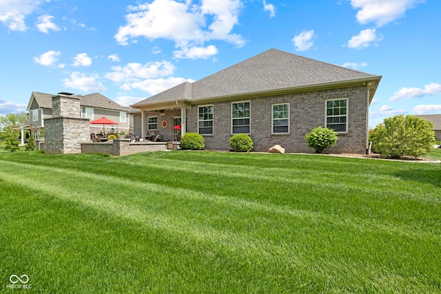 back of house with a lawn, a shingled roof, a patio area, and brick siding