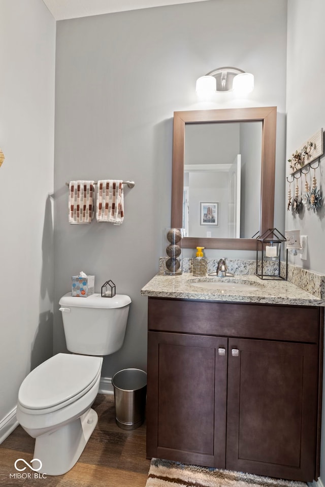 bathroom with baseboards, wood finished floors, toilet, and vanity