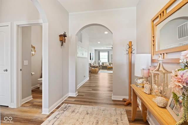 hallway featuring arched walkways, visible vents, wood finished floors, and recessed lighting