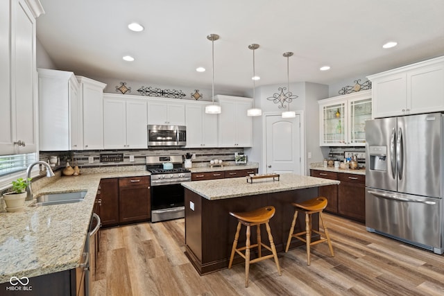 kitchen featuring a sink, light wood-style flooring, appliances with stainless steel finishes, and tasteful backsplash