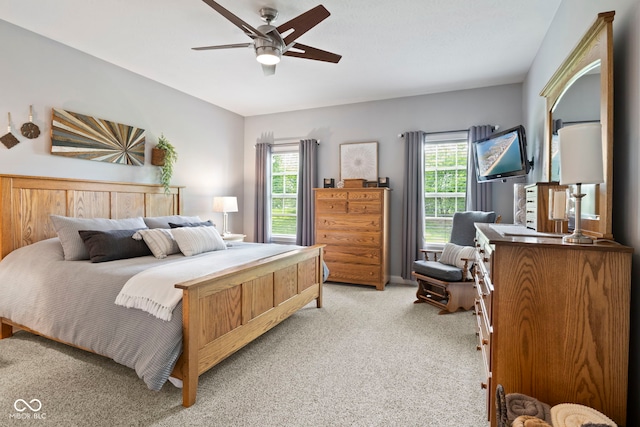 bedroom with a ceiling fan, light colored carpet, and multiple windows