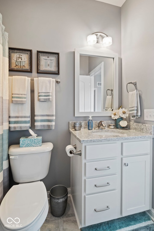 bathroom with vanity, baseboards, toilet, and tile patterned flooring