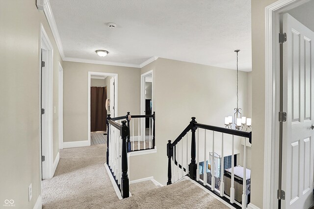 hall featuring an upstairs landing, a chandelier, carpet flooring, baseboards, and a textured ceiling