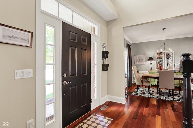 entryway with dark wood finished floors, baseboards, a chandelier, and crown molding