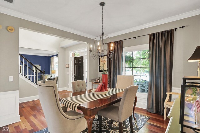 dining space featuring wood finished floors, a chandelier, crown molding, and stairs