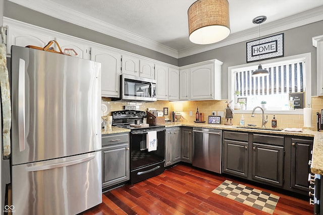 kitchen featuring appliances with stainless steel finishes, a sink, ornamental molding, white cabinetry, and backsplash