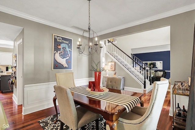 dining room with dark wood-style flooring, stairs, ornamental molding, a wainscoted wall, and a chandelier