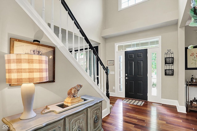 foyer entrance featuring dark wood finished floors, stairway, a high ceiling, and baseboards
