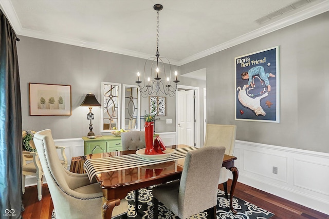 dining area featuring a chandelier, crown molding, dark wood-type flooring, and a wainscoted wall